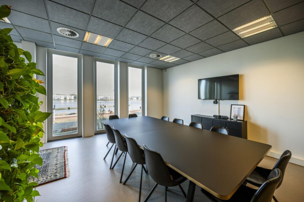 Vergaderruimte aan de De Ruijterkade met lange tafel, moderne inrichting en uitzicht op het water.